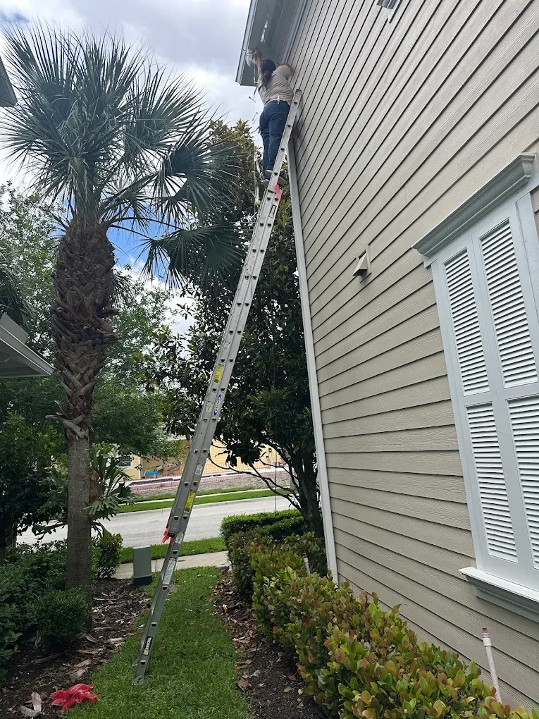 Swift Wildlife technician sealing a soffit from a ladder
